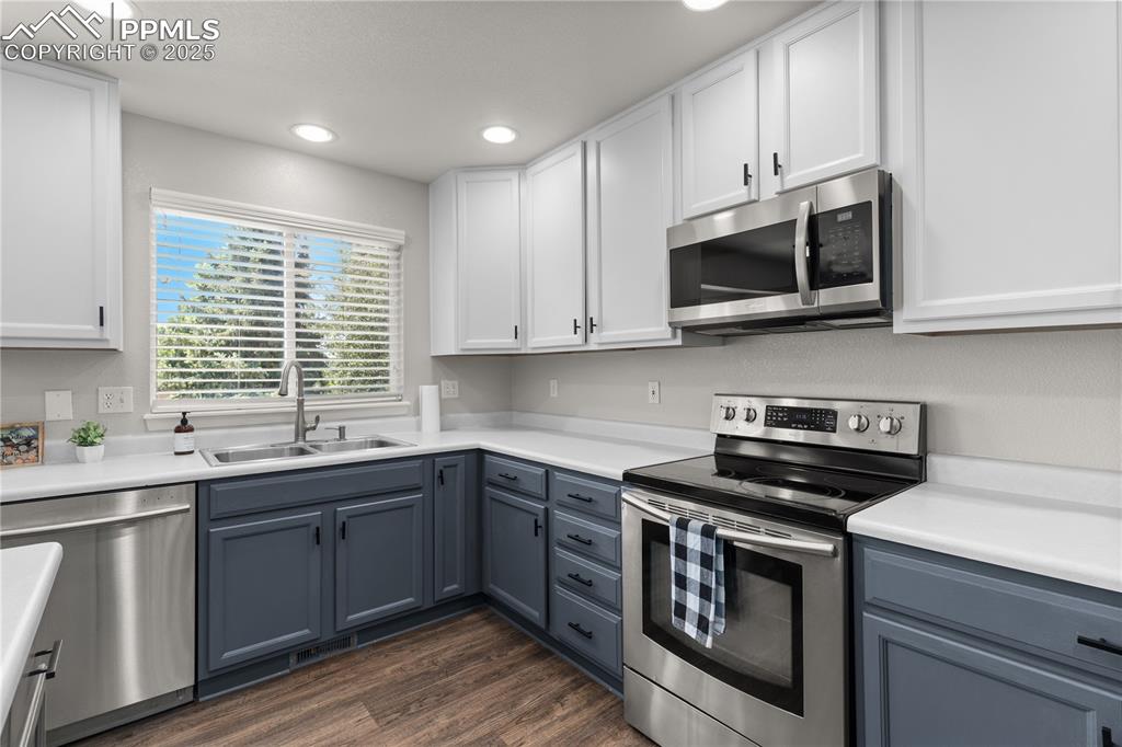 Image 10 of 31: Kitchen with appliances with stainless steel finishes, white cabinets, rece