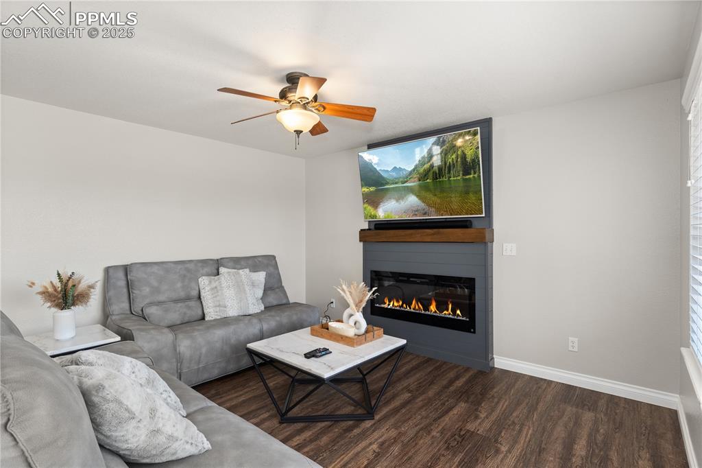 Image 13 of 31: Living area featuring a glass covered fireplace, wood finished floors, ceil