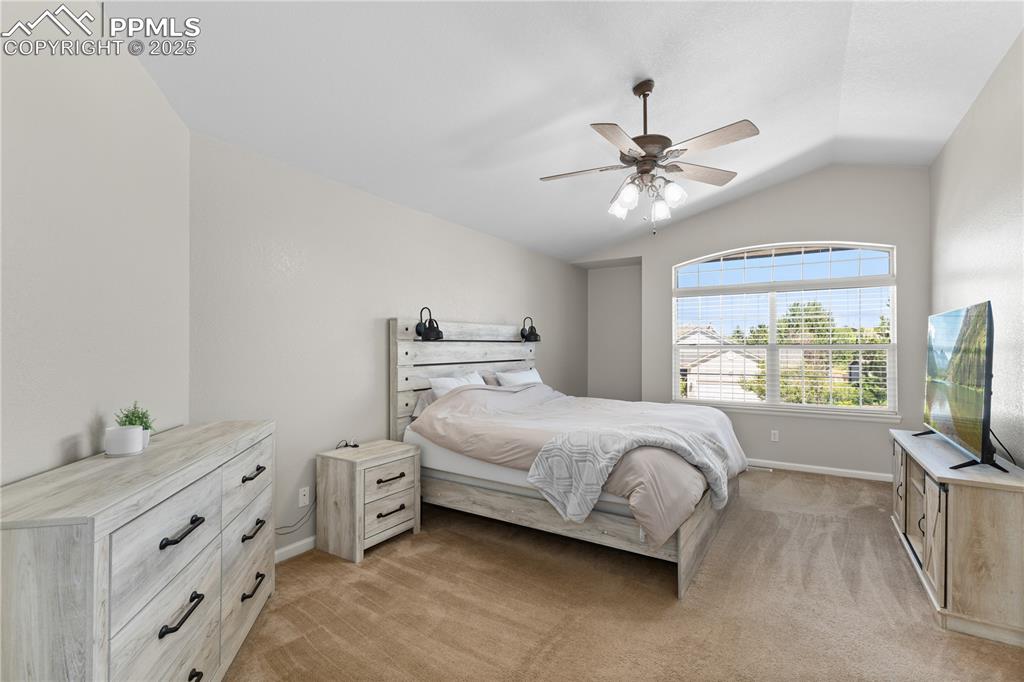 Image 22 of 31: Bedroom with lofted ceiling, light carpet, and ceiling fan