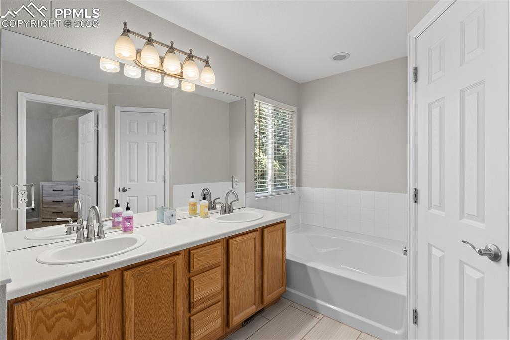 Image 25 of 31: Full bathroom featuring double vanity, a garden tub, and tile patterned flo