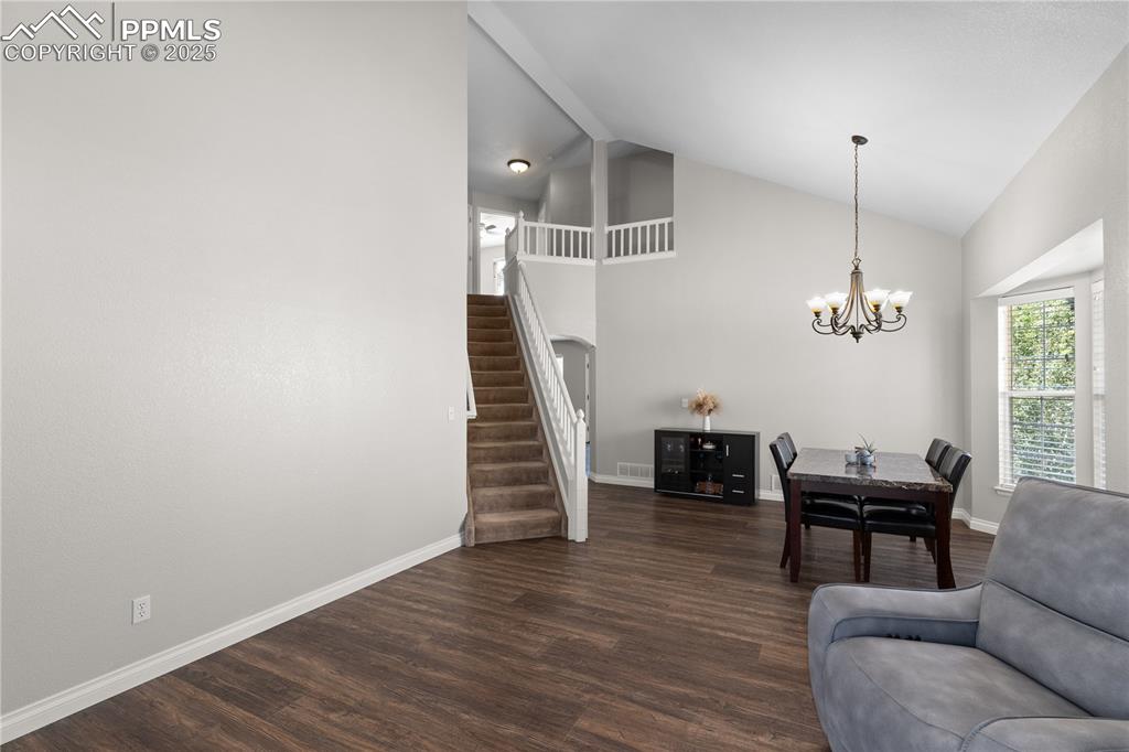 Image 4 of 31: Living room featuring stairs, a chandelier, dark wood-style flooring, and h