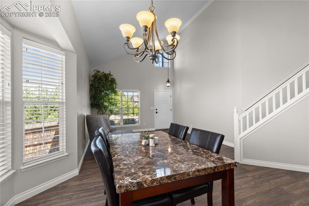 Image 6 of 31: Dining space with a chandelier, dark wood finished floors, stairway, and hi