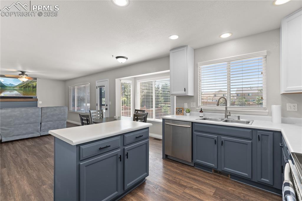 Image 7 of 31: Kitchen with dishwasher, range, dark wood-style flooring, white cabinetry,