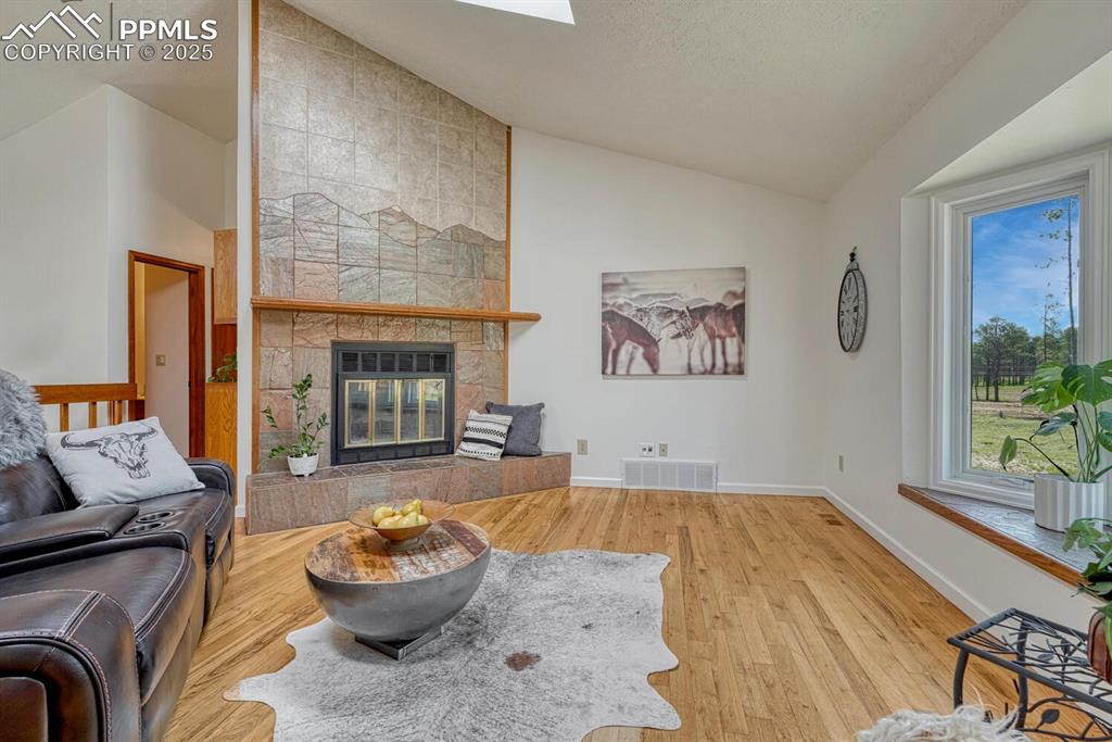 Image 4 of 48: Living room with gorgeous hearthstone, natural wood floors and bay window