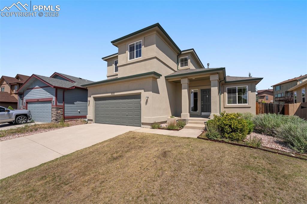 Caption: Prairie-style home with stucco siding, an attached garage, and driveway