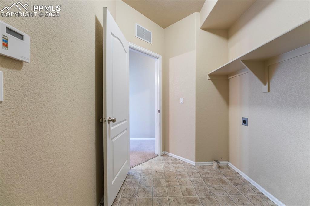 Image 15 of 49: Washroom with hookup for an electric dryer and stone finish flooring