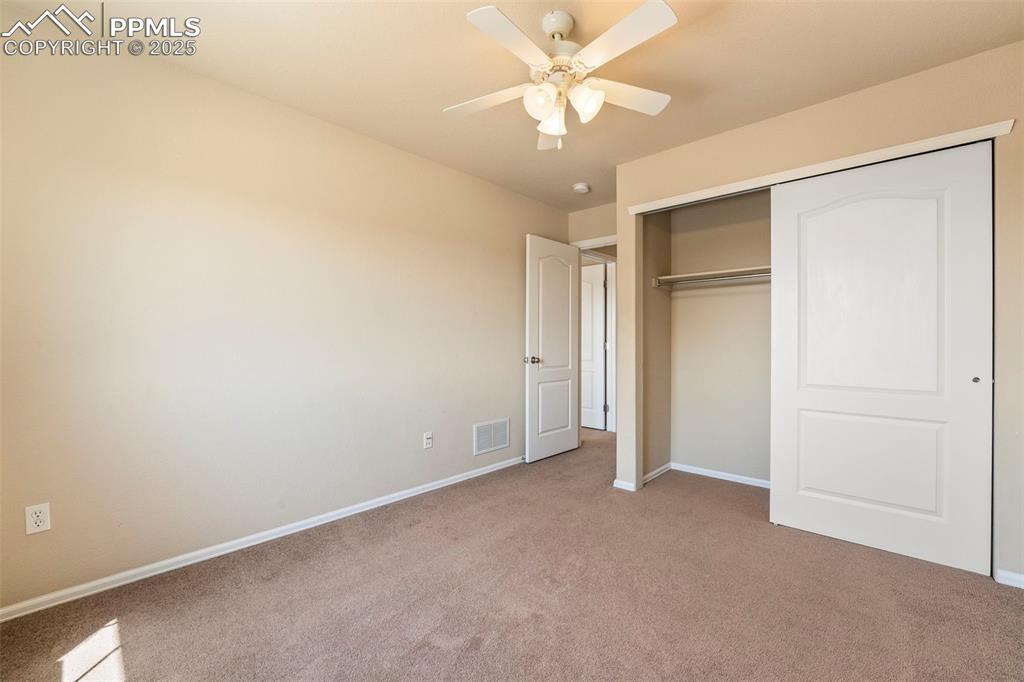 Image 21 of 49: Unfurnished bedroom featuring light carpet, a closet, and a ceiling fan