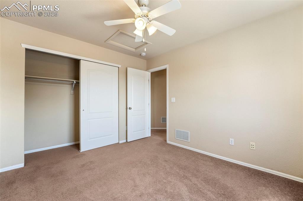 Image 23 of 49: Unfurnished bedroom with carpet floors, a closet, attic access, and ceiling