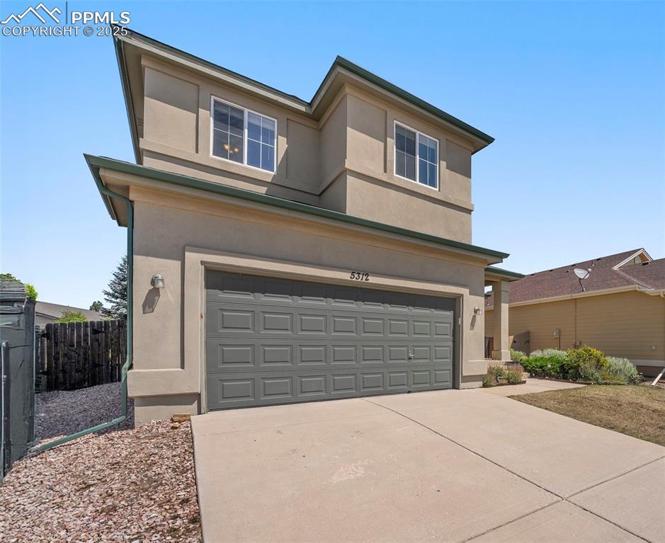 Image 3 of 49: View of front of property featuring a garage, driveway, and stucco siding