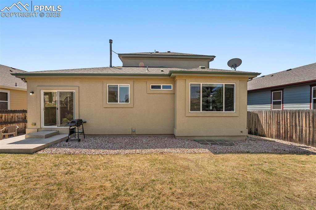 Image 36 of 49: Rear view of house with a shingled roof and stucco siding
