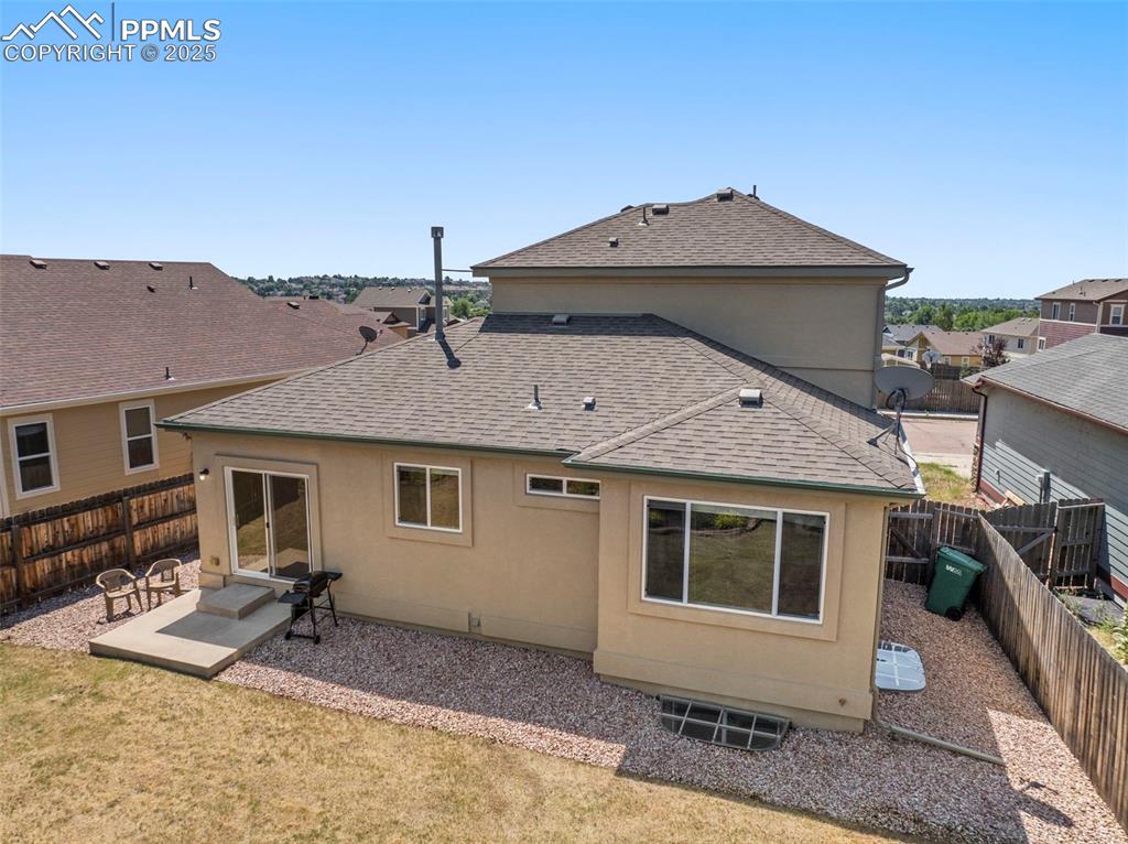 Image 43 of 49: Back of house with a shingled roof, a fenced backyard, stucco siding, a pat