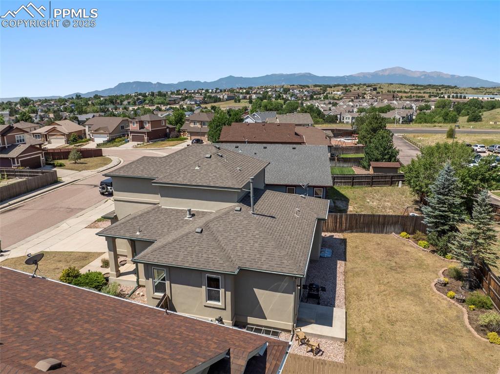 Image 44 of 49: Aerial view of residential area featuring a mountainous background