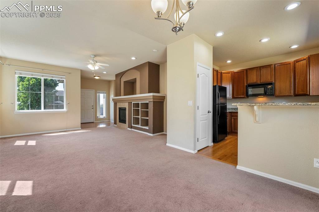 Image 6 of 49: Kitchen with light colored carpet, open floor plan, brown cabinetry, a ceil