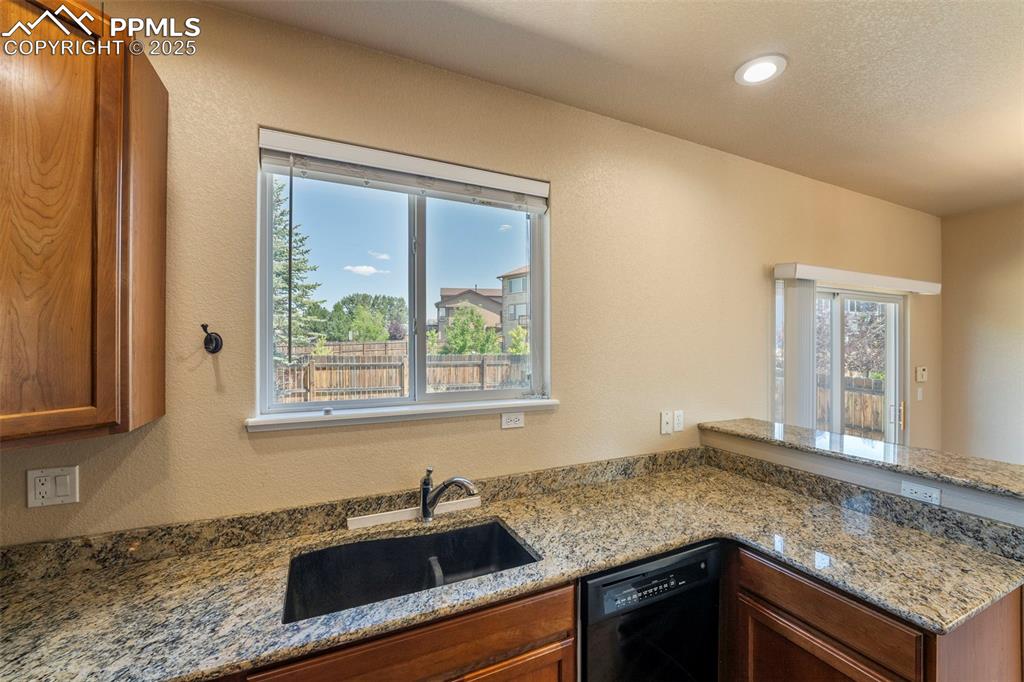 Image 9 of 49: Kitchen featuring healthy amount of natural light, dishwasher, brown cabine