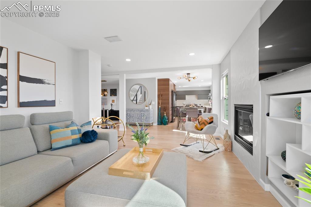 Image 10 of 47: Living area featuring a glass covered fireplace, light wood-style floors, a