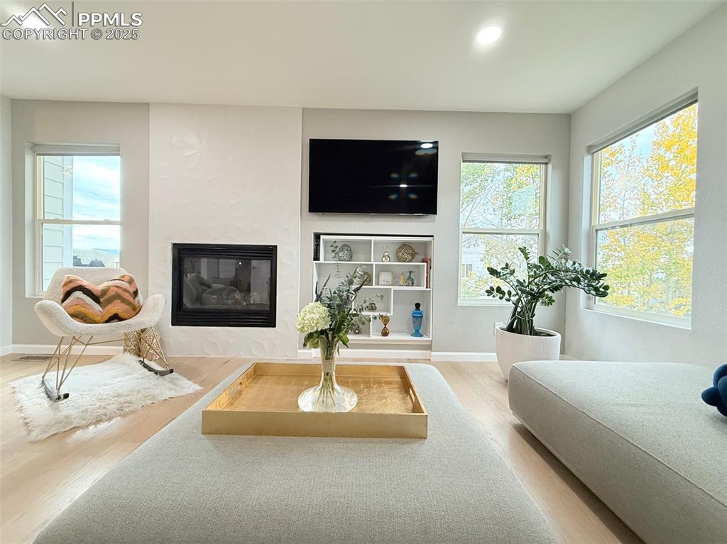 Image 11 of 47: Living room featuring a glass covered fireplace, plenty of natural light, l