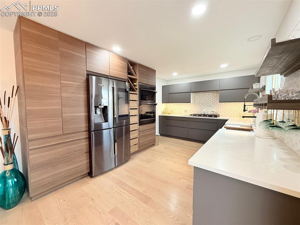 Image 21 of 47: Kitchen with appliances with stainless steel finishes, light wood-type floo