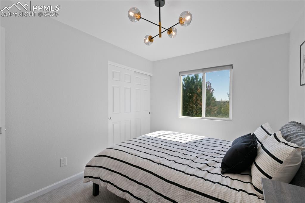 Image 24 of 47: Carpeted bedroom with a chandelier and baseboards