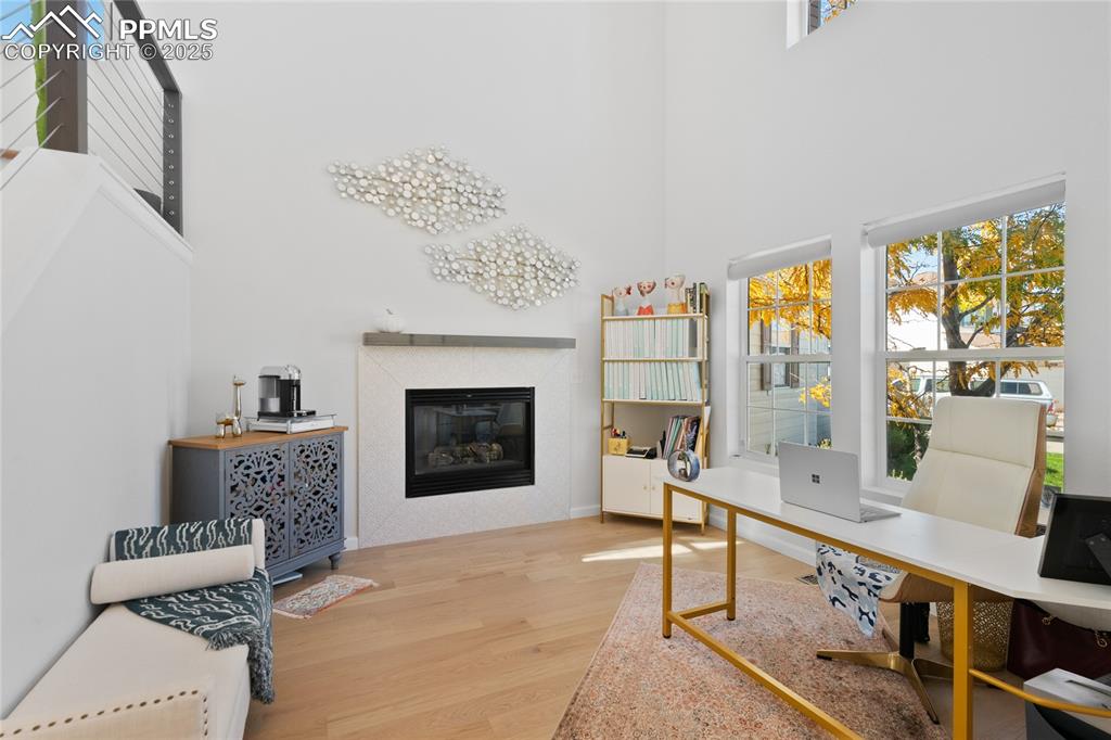Image 3 of 47: Office with light wood-type flooring, a high ceiling, and a glass covered f