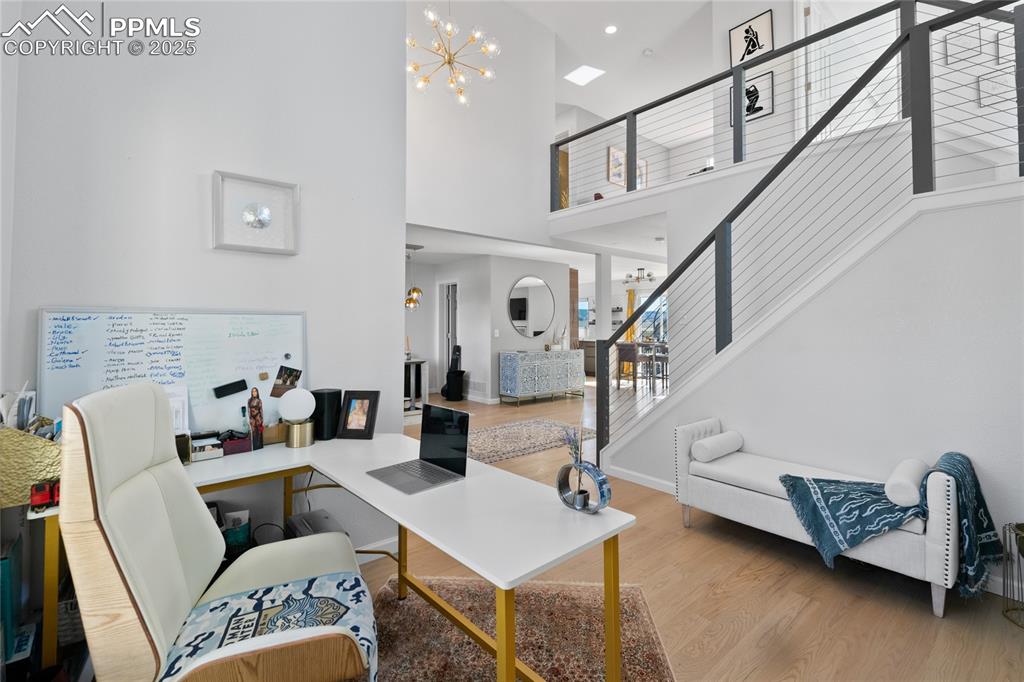 Image 4 of 47: Office space featuring wood finished floors, a towering ceiling, and a chan
