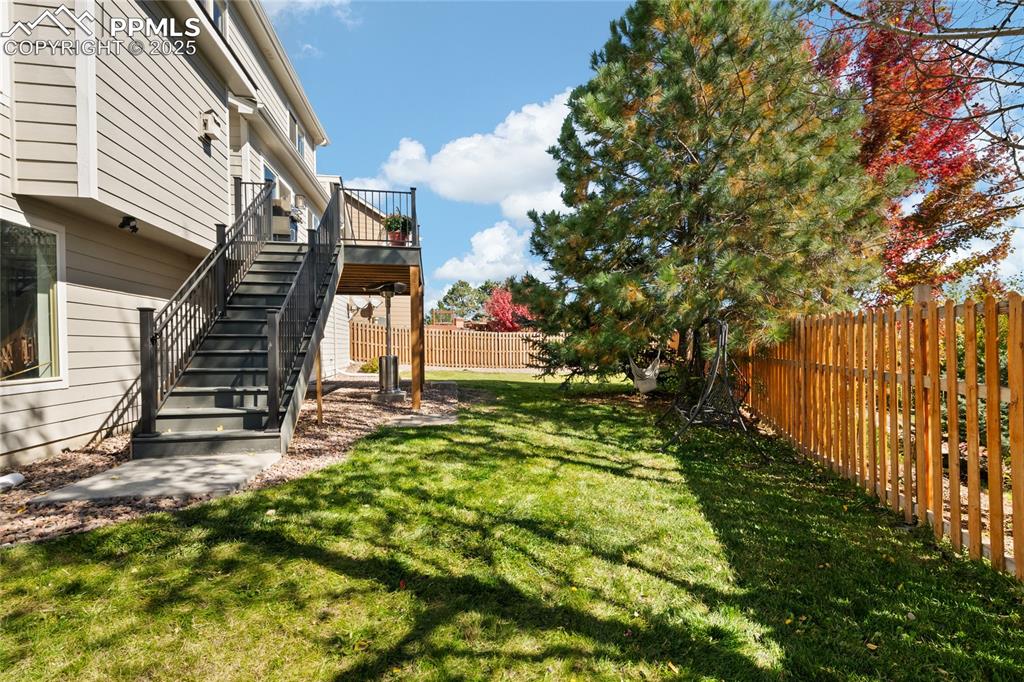 Image 44 of 47: Fenced backyard featuring stairs, a deck, and a patio area