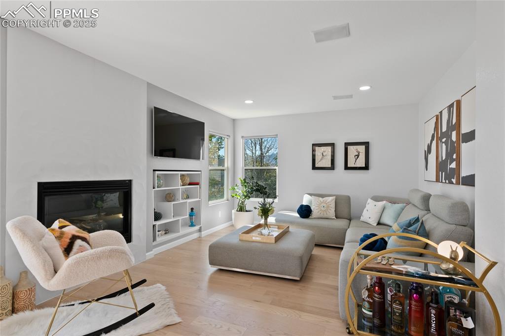 Image 9 of 47: Living area featuring wood finished floors, a fireplace, and recessed light
