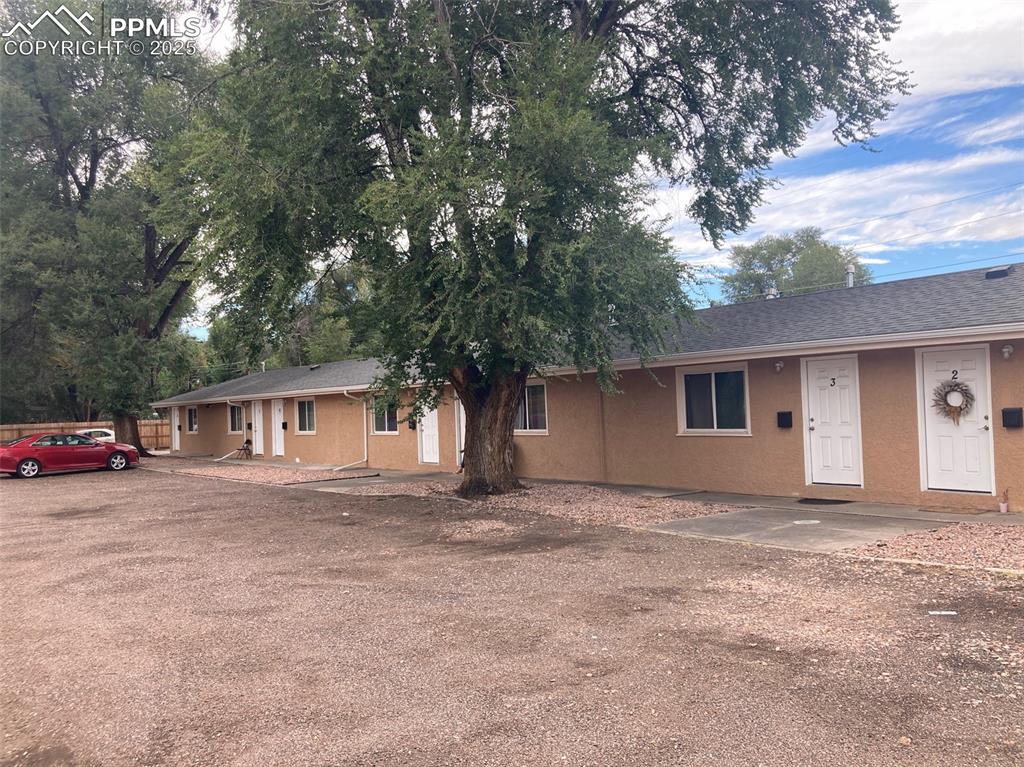 Image 12 of 26: Ranch-style house with stucco siding, roof with shingles, and a patio