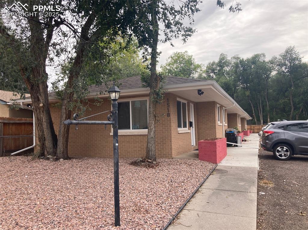 Image 13 of 26: View of side of property featuring brick siding and a shingled roof