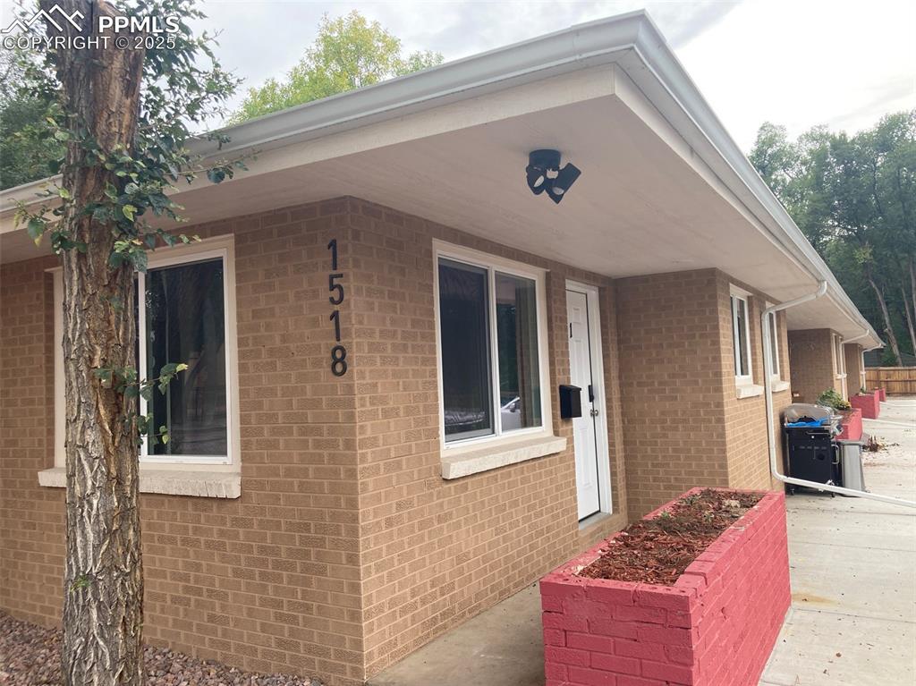 Image 14 of 26: View of side of home with covered porch and brick siding