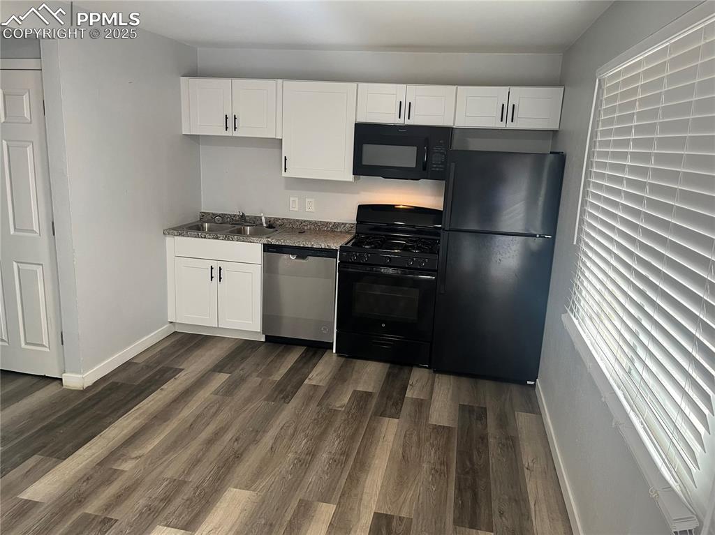Image 19 of 26: Kitchen with black appliances, white cabinetry, dark wood-style floors, and