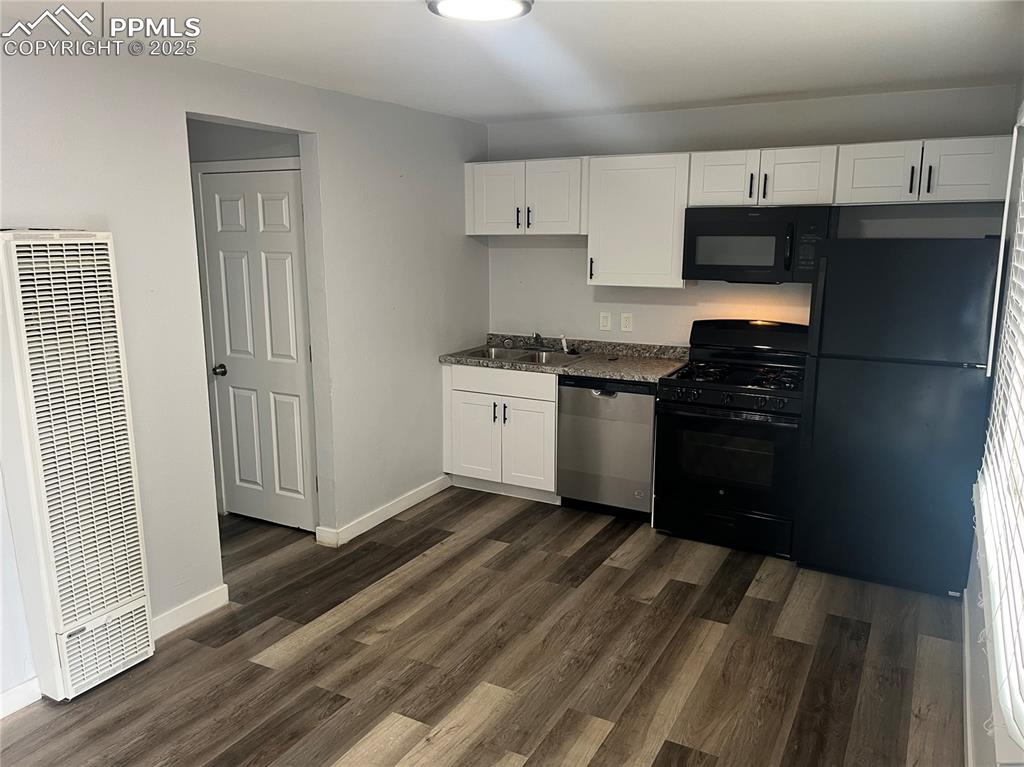 Image 20 of 26: Kitchen featuring white cabinetry, black appliances, a heating unit, and da