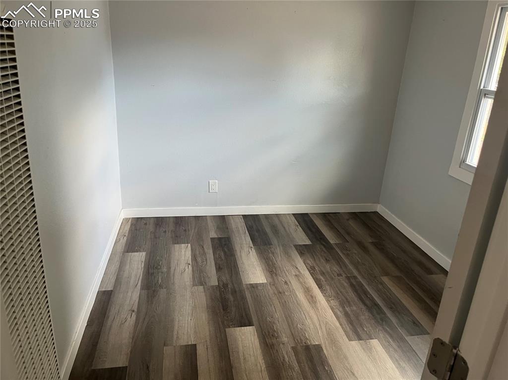 Image 23 of 26: Spare room featuring a heating unit and dark wood-type flooring