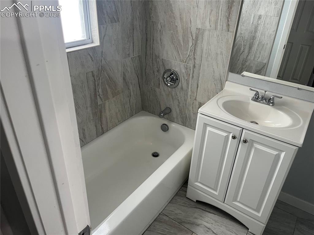 Image 25 of 26: Full bath with vanity,  shower combination, and marble look tile flooring