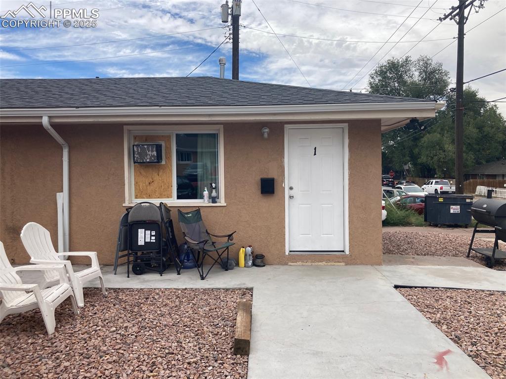 Image 8 of 26: View of exterior entry featuring stucco siding and a shingled roof