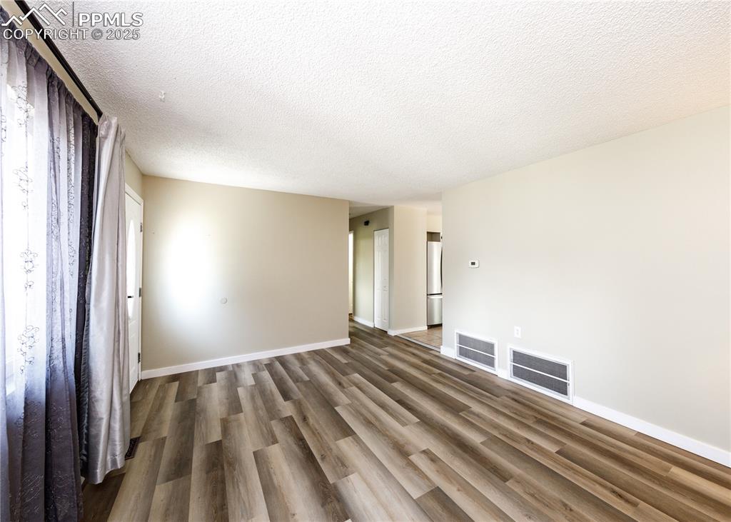 Image 11 of 48: Unfurnished living room with a textured ceiling and wood finished floors
