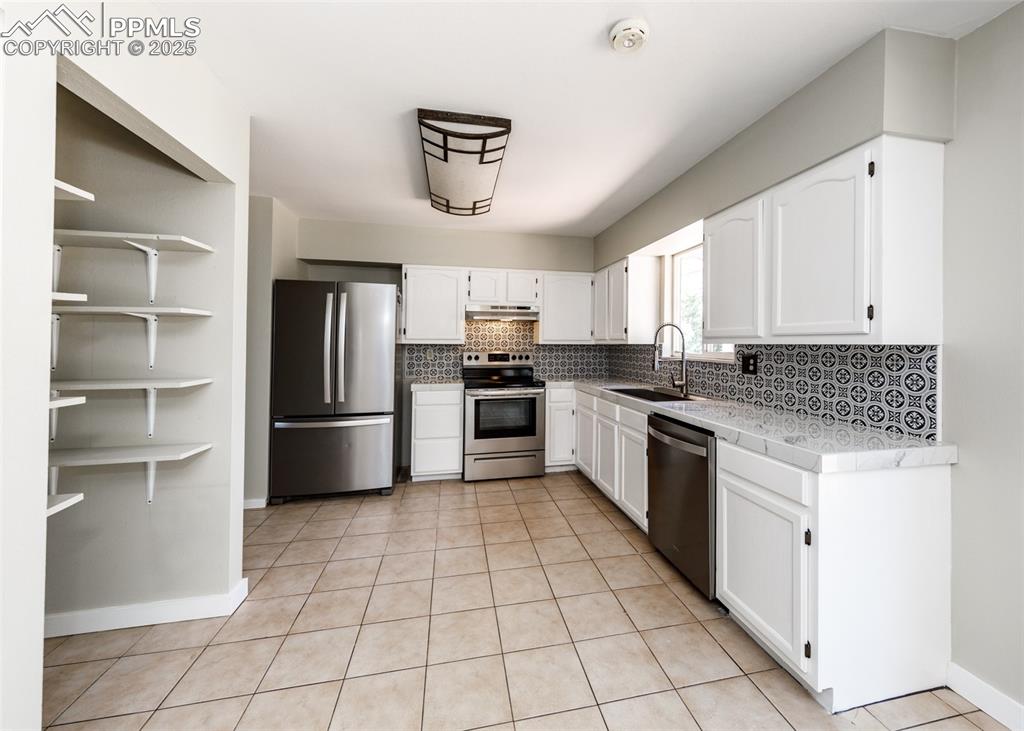 Image 13 of 48: Kitchen with appliances with stainless steel finishes, white cabinets, ligh