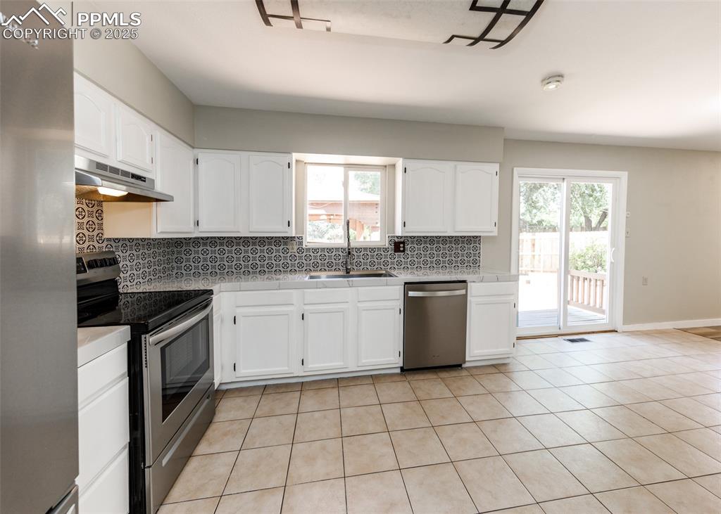 Image 14 of 48: Kitchen with tasteful backsplash, appliances with stainless steel finishes,