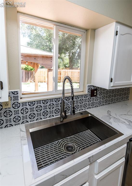 Image 17 of 48: Kitchen view of white cabinets, backsplash, and light stone countertops