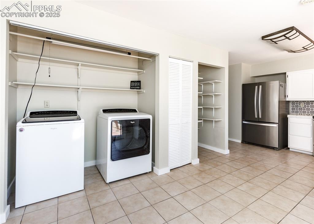 Image 19 of 48: Laundry area with light tile patterned flooring and separate washer and dry