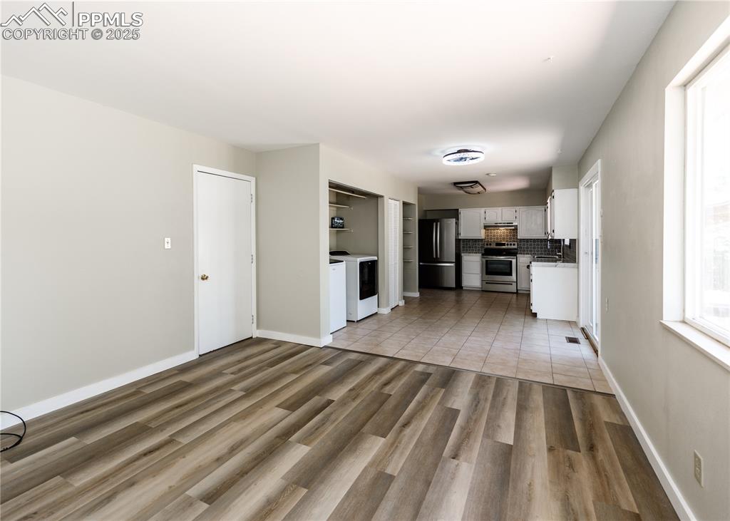 Image 25 of 48: Unfurnished living room featuring washing machine and dryer and light wood-