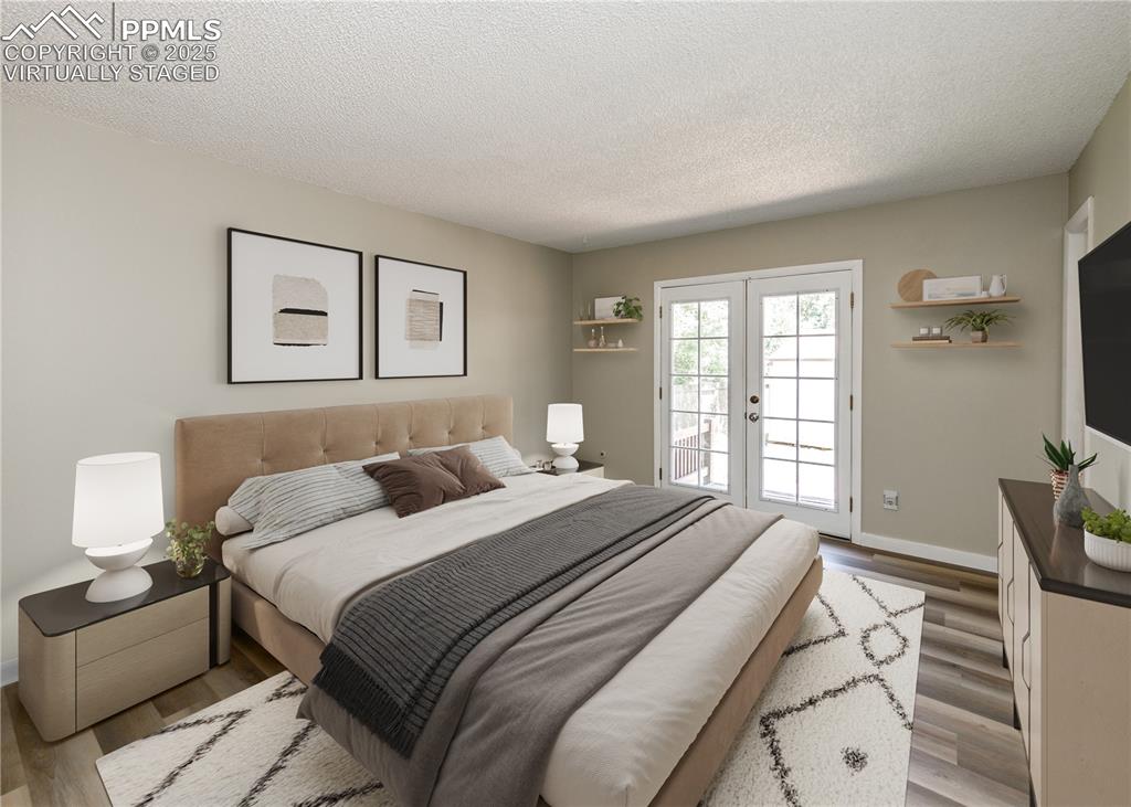 Image 30 of 48: Bedroom with wood finished floors, french doors, a textured ceiling, and ac