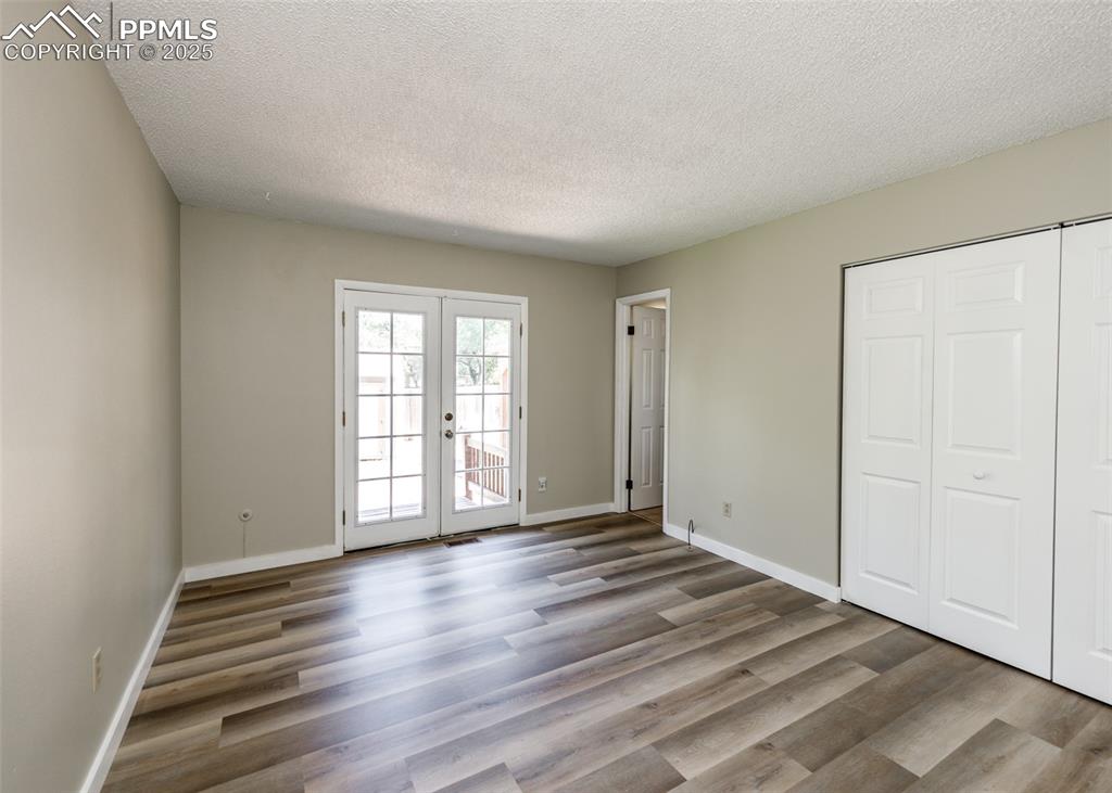 Image 31 of 48: Unfurnished bedroom with a textured ceiling, access to outside, wood finish