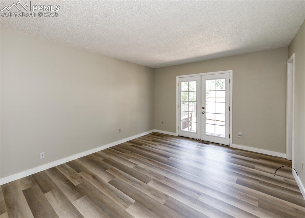 Image 32 of 48: Unfurnished room featuring french doors, wood finished floors, and a textur