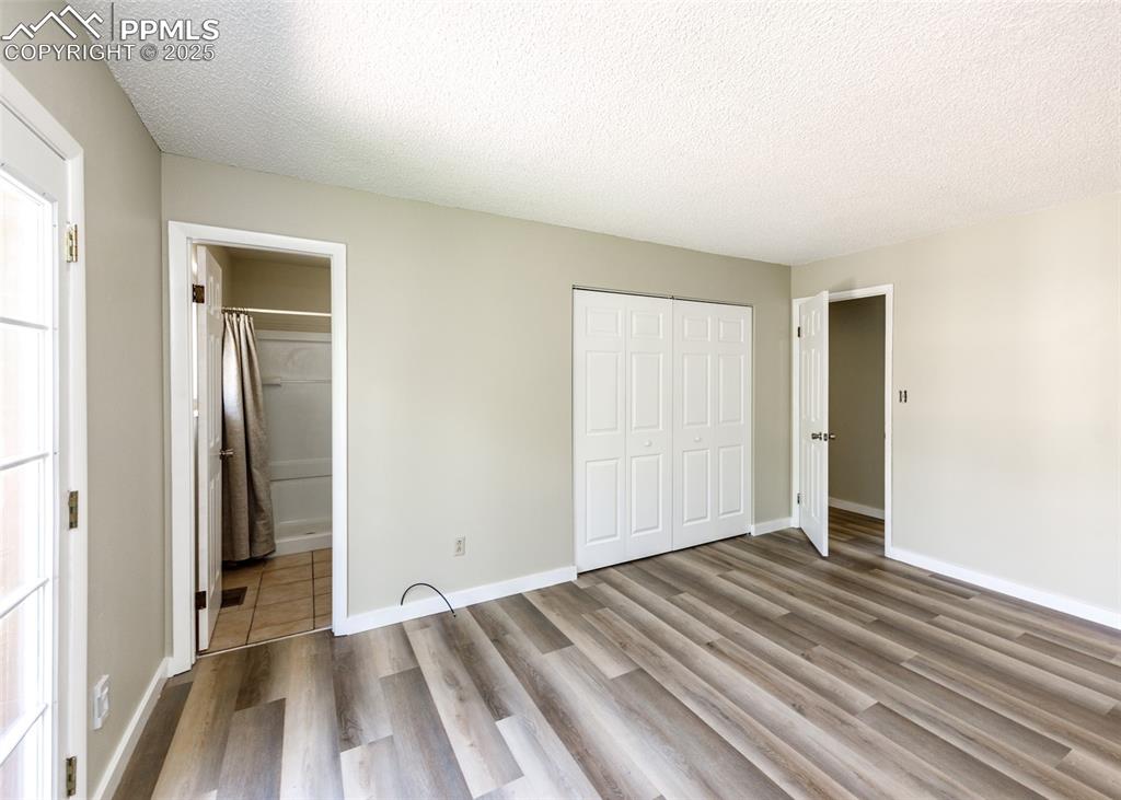 Image 33 of 48: Unfurnished bedroom with a textured ceiling, wood finished floors, a closet