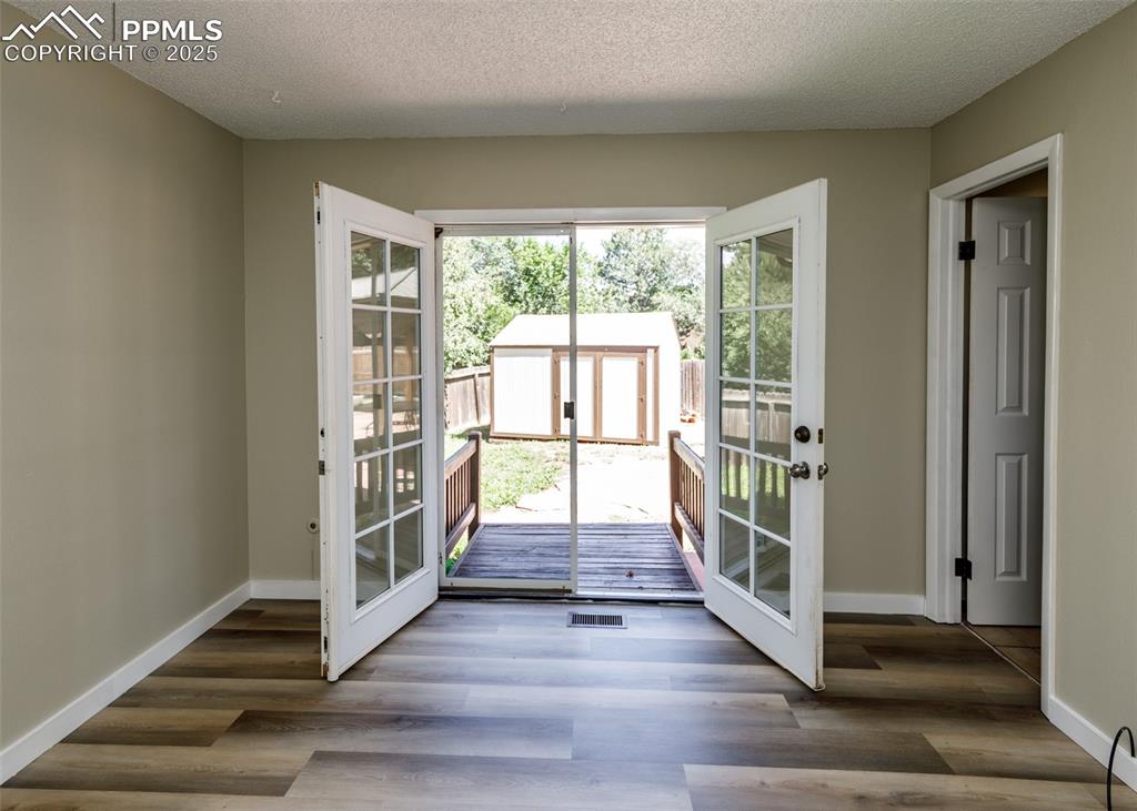 Image 34 of 48: Doorway to outside featuring a textured ceiling and wood finished floors