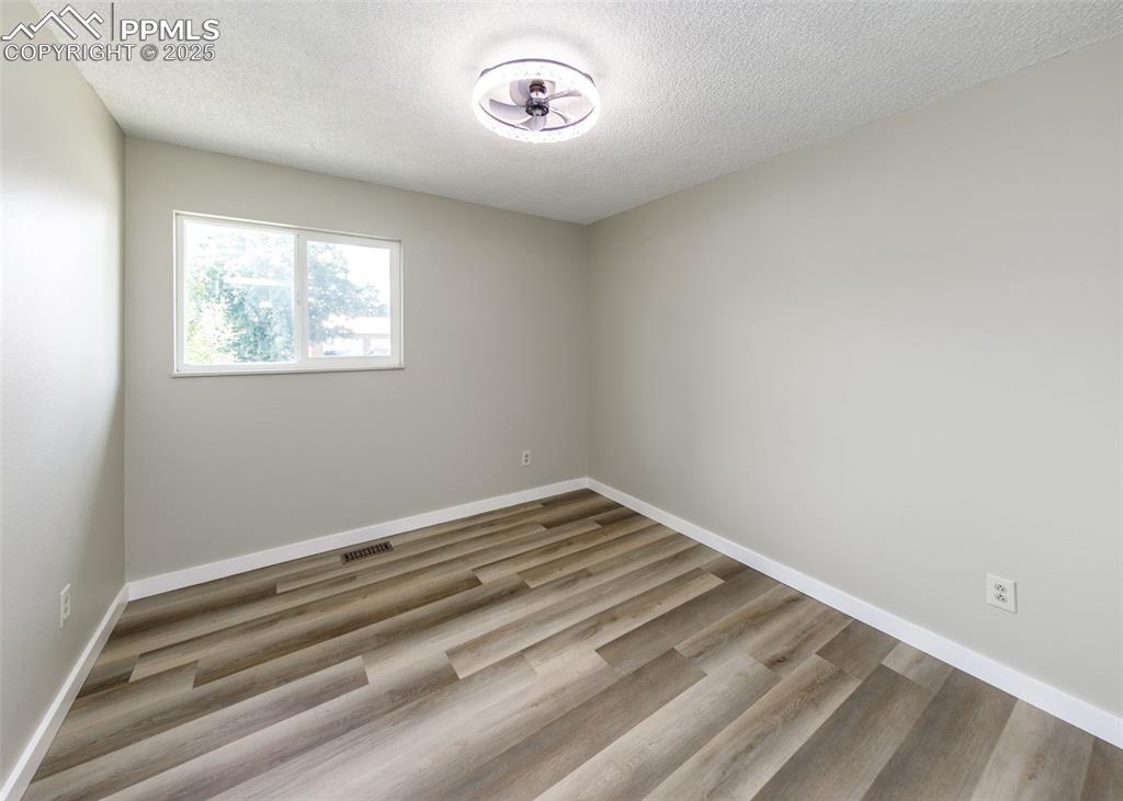 Image 36 of 48: Empty room with a textured ceiling and wood finished floors