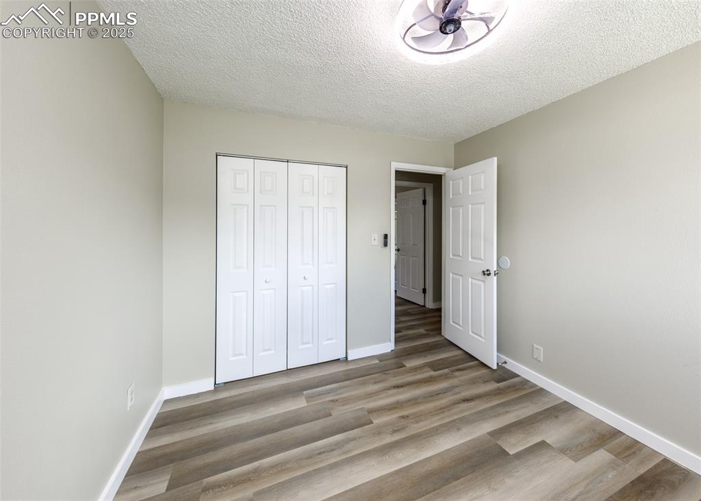 Image 37 of 48: Unfurnished bedroom with a textured ceiling, light wood-style floors, and a