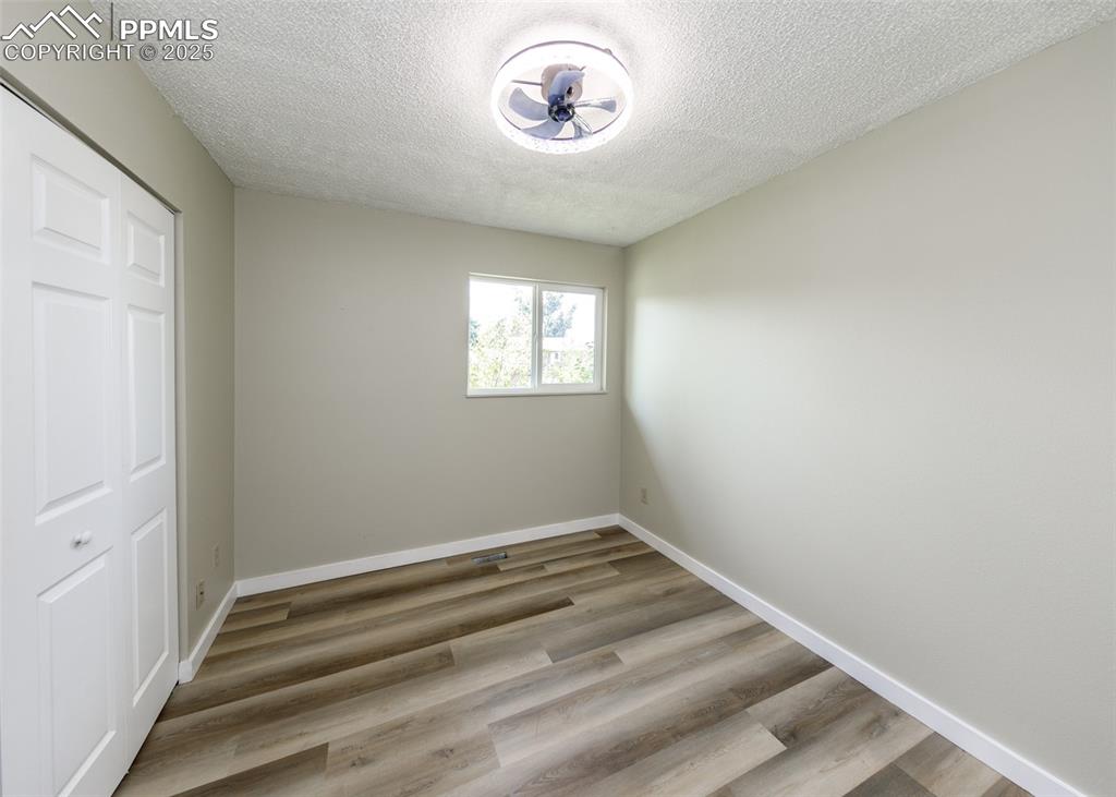 Image 38 of 48: Unfurnished bedroom with a closet, a textured ceiling, and light wood-style