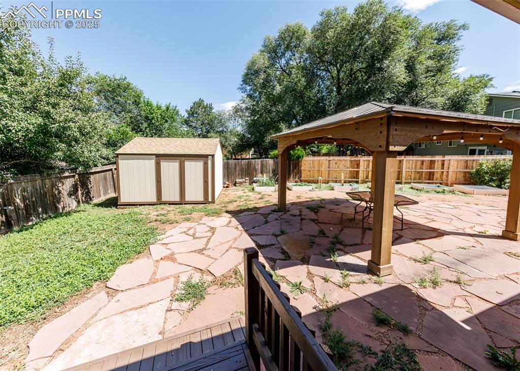 Image 42 of 48: Fenced backyard featuring a patio, a gazebo, and a storage unit