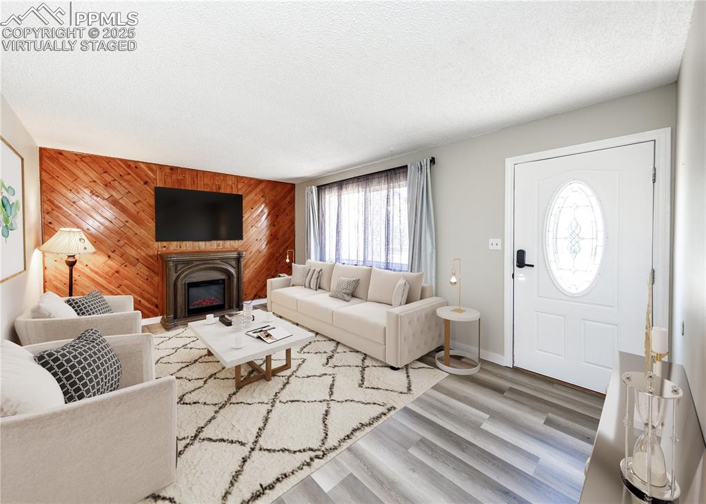 Image 6 of 48: Living area with wooden walls, a glass covered fireplace, a textured ceilin
